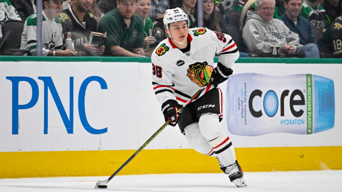 Connor Bedard handles the puck in a white Blackhawks jersey